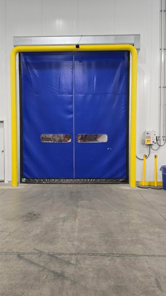 High speed roll up doors with goal post bollards between cold dock and ambient warehouse.