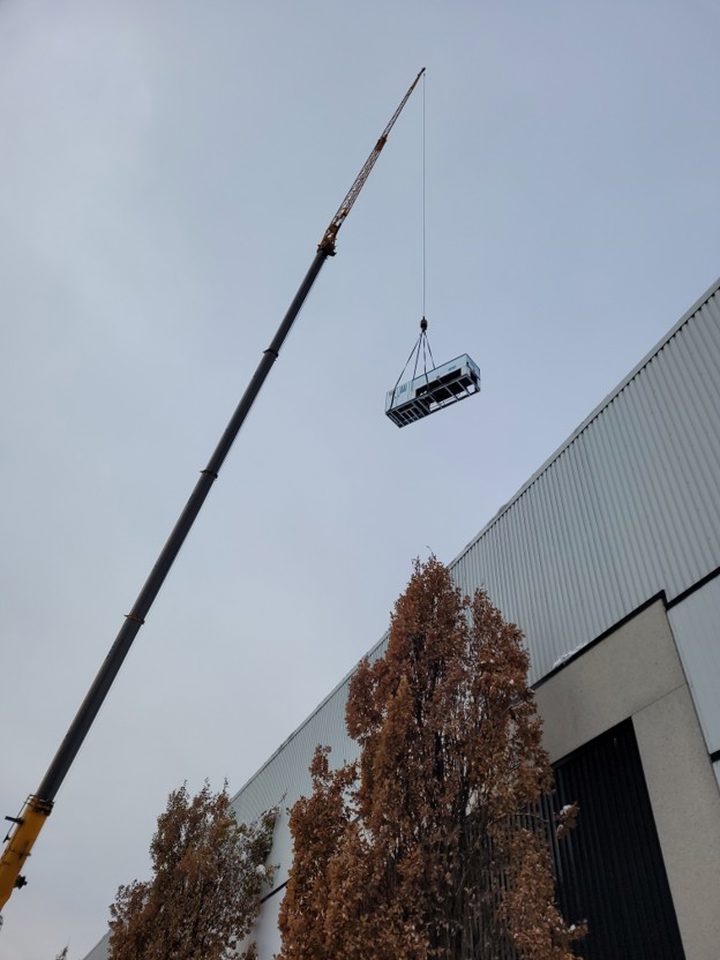 Crane hoisting one of seventeen 30 HP roof mounted refrigeration units.
